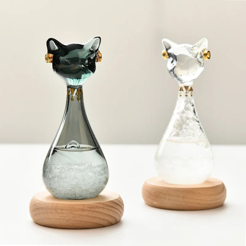 Two cat-shaped glass bottles with wooden bases on a light background