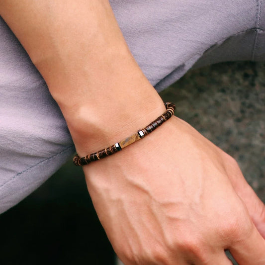 Close-up of a wrist wearing a brown beaded bracelet with a blurred background