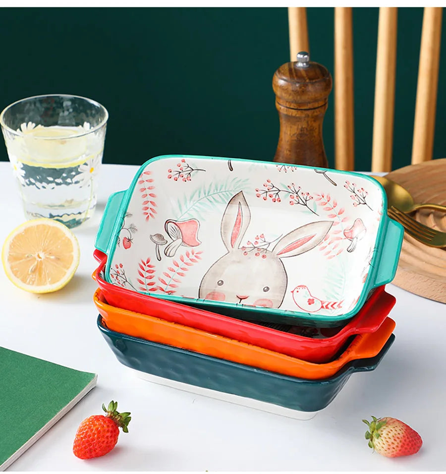 Stack of colorful ceramic trays with rabbit design on a table with lemon and strawberries.
