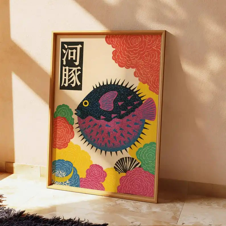 Colourful Japanese-inspired puffer fish canvas artwork featuring a dark blue and pink fish surrounded by stylised coral, yellow and teal flowers, displayed in a light wooden frame.