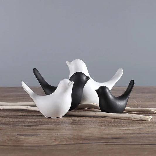 Set of black and white ceramic birds on a wooden surface with a gray background
