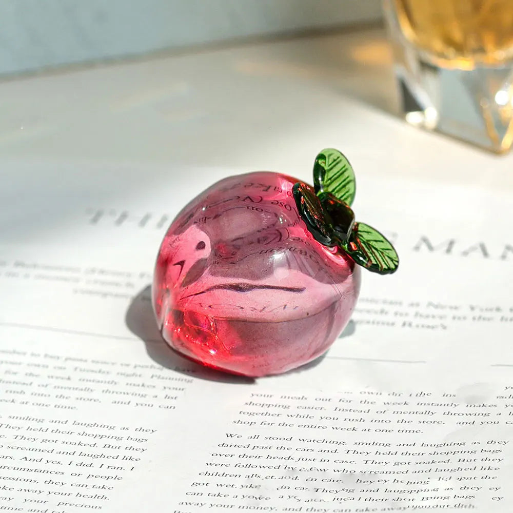 Pink glass cherry with a green leaf on a book page