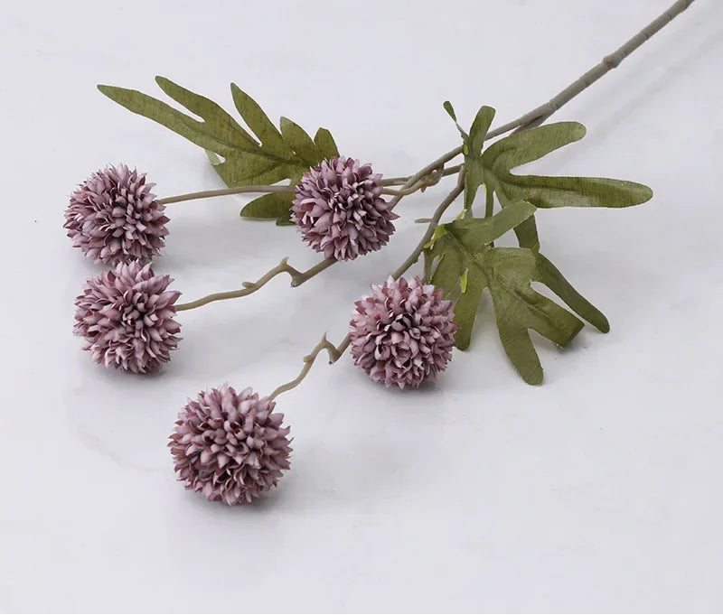 Artificial flower branch with purple flowers and green leaves on a white background