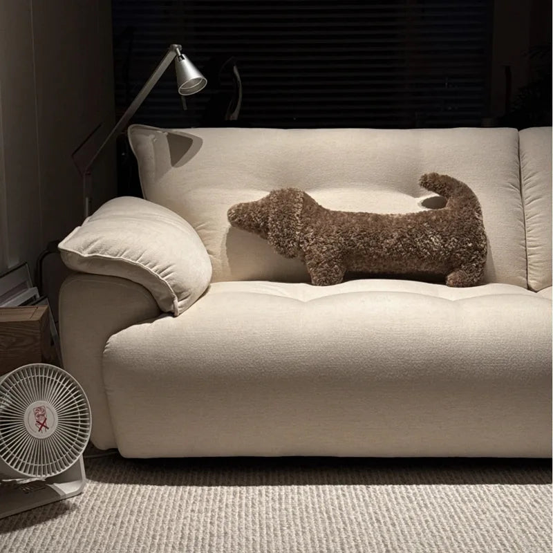 dachshund-shaped cushion on a Beige sofa with a decorative pillow shaped like a dog in a living room setting.