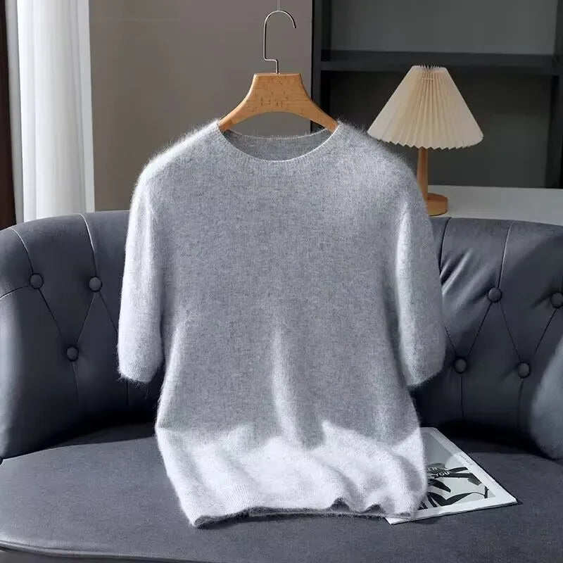 Gray sweater on a hanger over a gray sofa with a lamp in the background