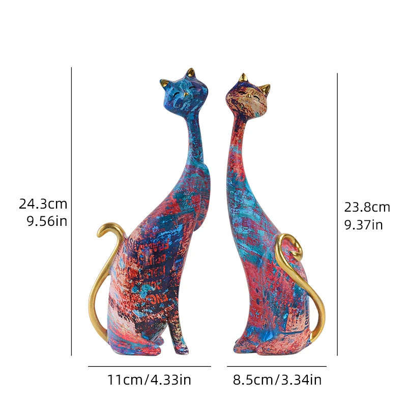 Pair of decorative resin cat sculptures with elongated modern silhouettes and artistic finishes, displayed as contemporary home decor on a tabletop.