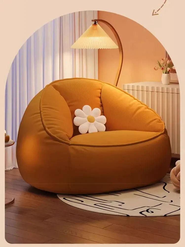 Orange bean bag chair with a white flower pillow in a room setting.