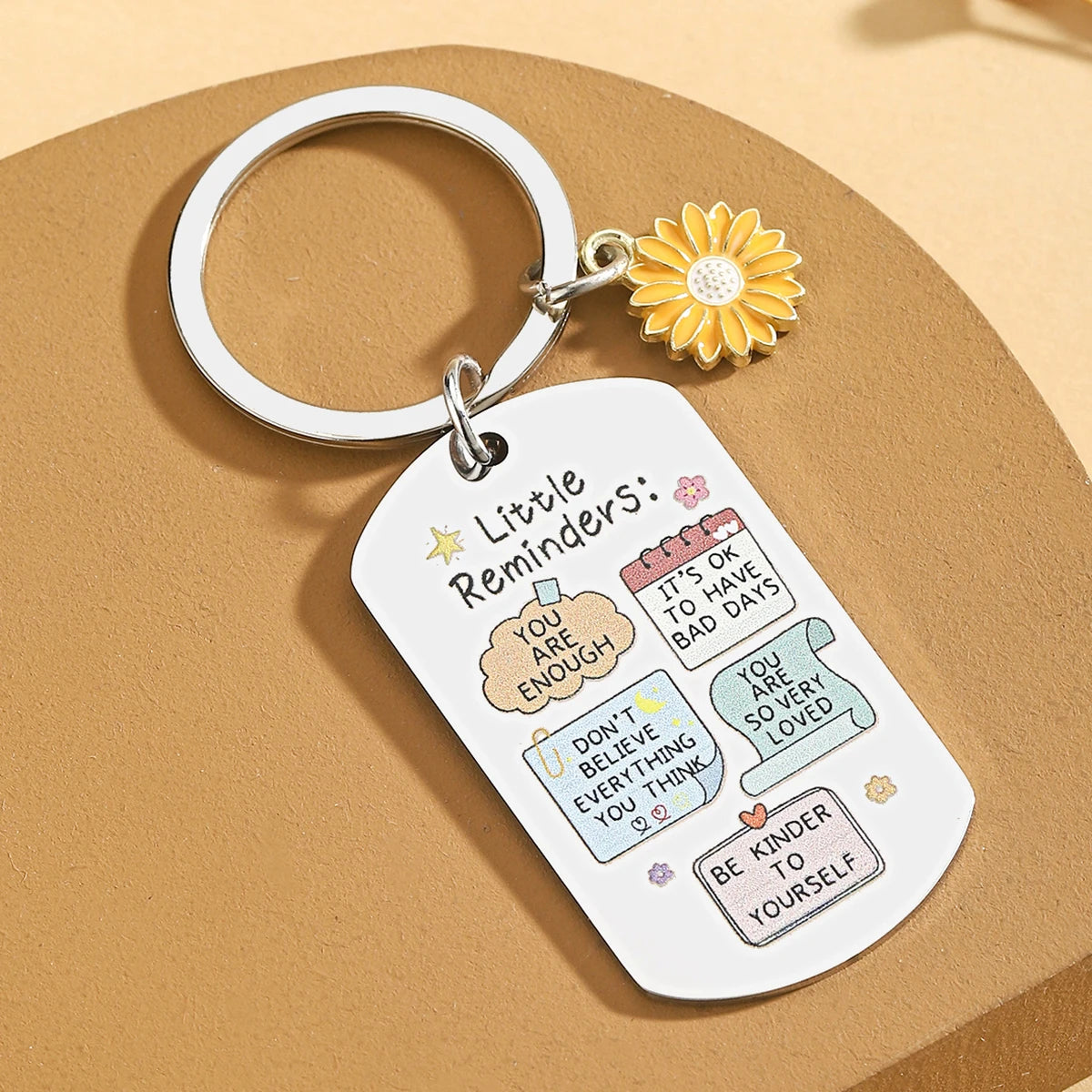 Keychain with motivational phrases and a sunflower charm on a beige background