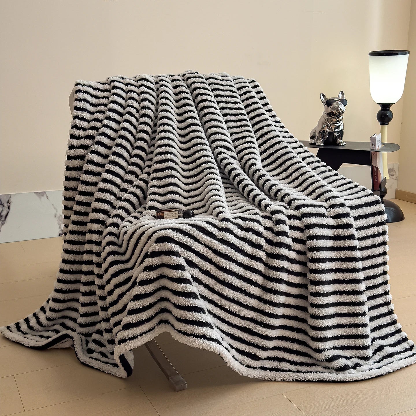 Black and white striped blanket draped over a chair in a room with a lamp and small table.