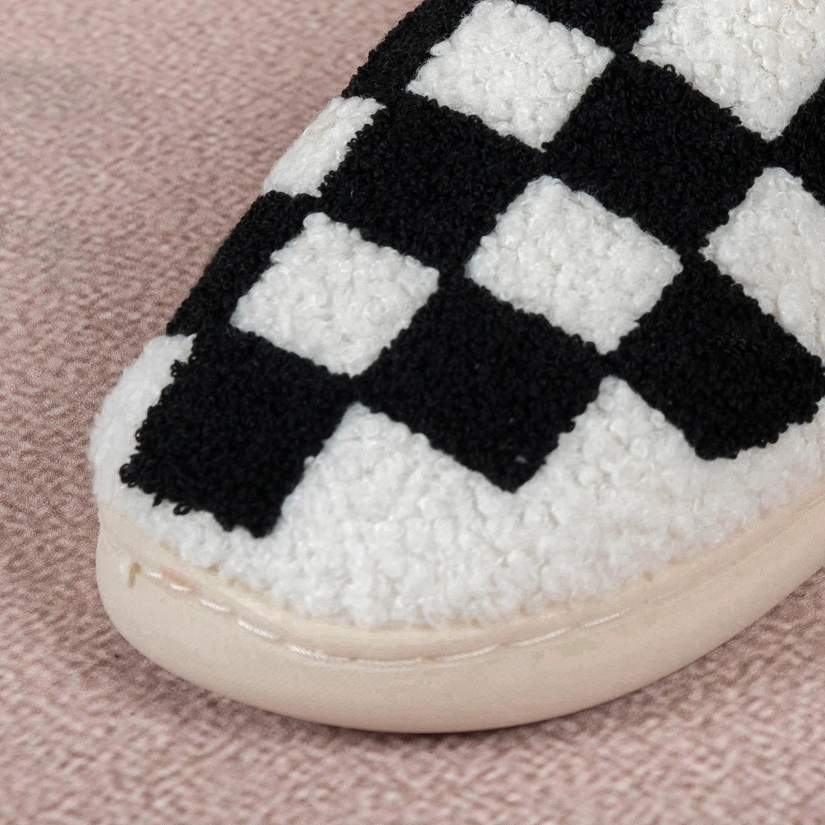 Close-up of a checkered slipper with white and black pattern on a pink surface