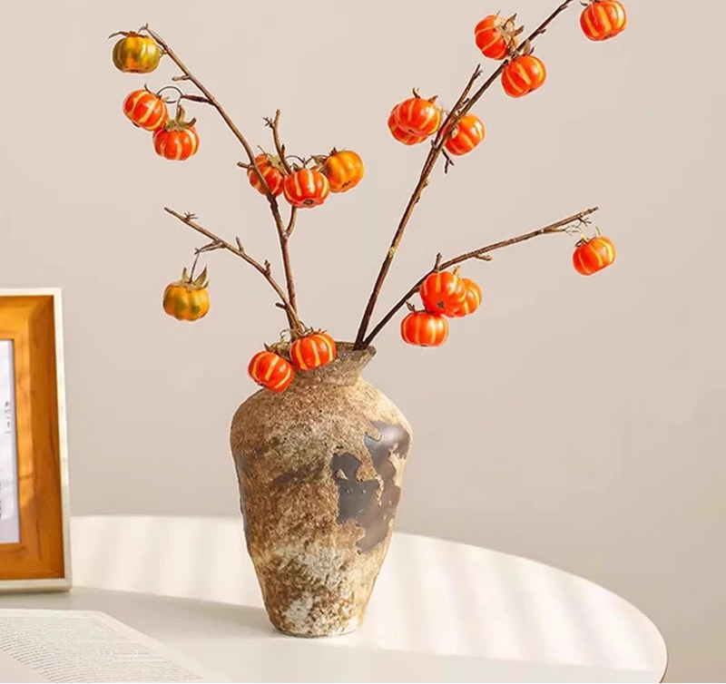 Decorative Wabi-sabi ceramic vase with branches and orange fruits on a light background