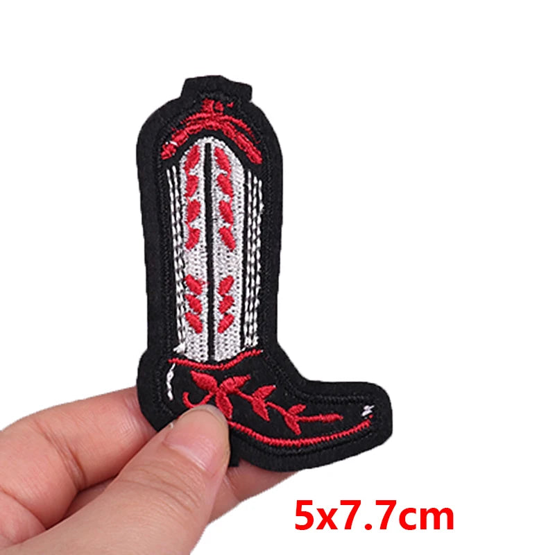 Small embroidered patch of a cowboy boot held by a hand with dimensions 5x7.7cm.