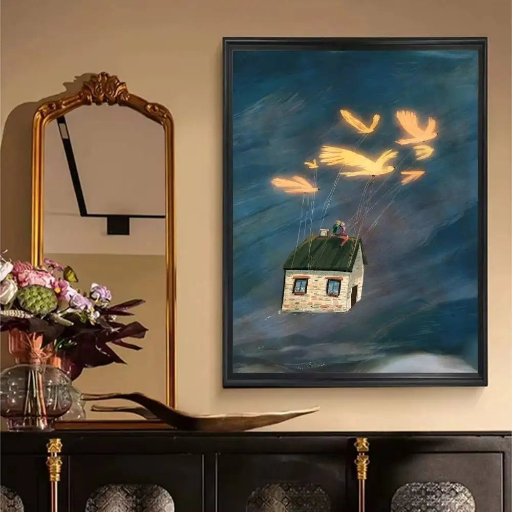 Framed artwork of a house being lifted by balloons on a wall above a decorative cabinet.