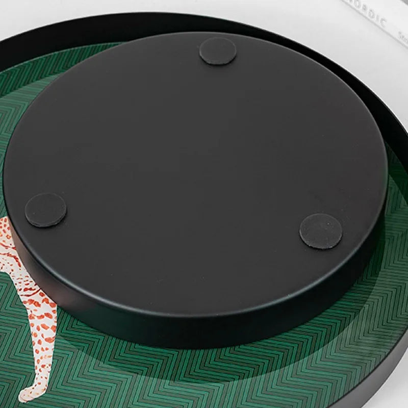Black round object on a green patterned surface with a white background