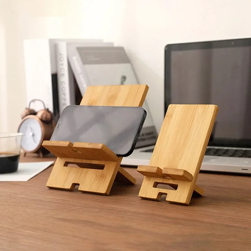 Wooden phone and tablet stands on a desk with a laptop in the background