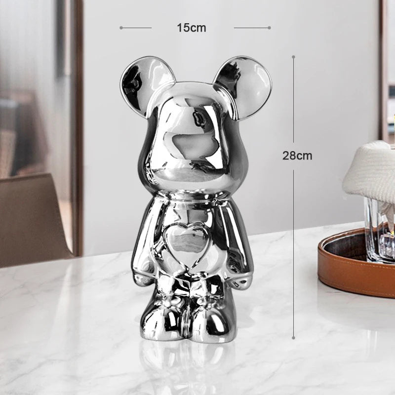 Silver teddy bear figurine with heart design on a white surface, with dimensions displayed.