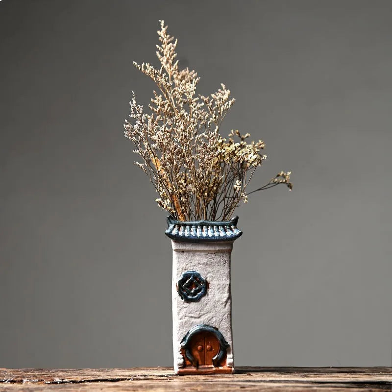 Decorative vase with dried flowers on a wooden surface against a gray background