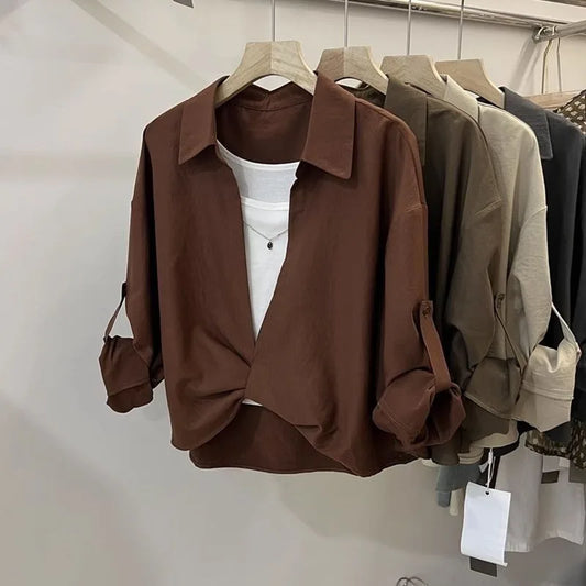 Women’s loose fit layered look blouse with long sleeves and collared neckline in neutral colours on a clothing rack