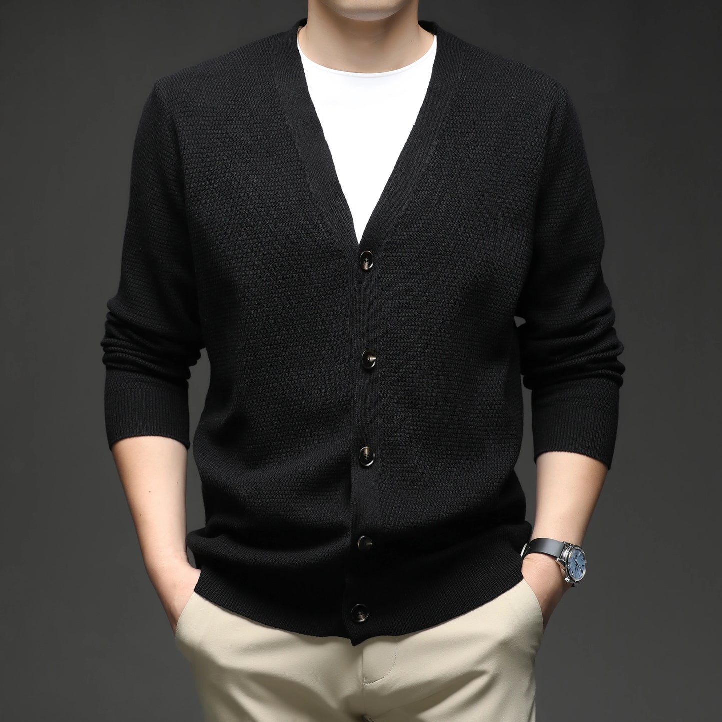 Black cardigan over a white shirt with beige pants on a dark background