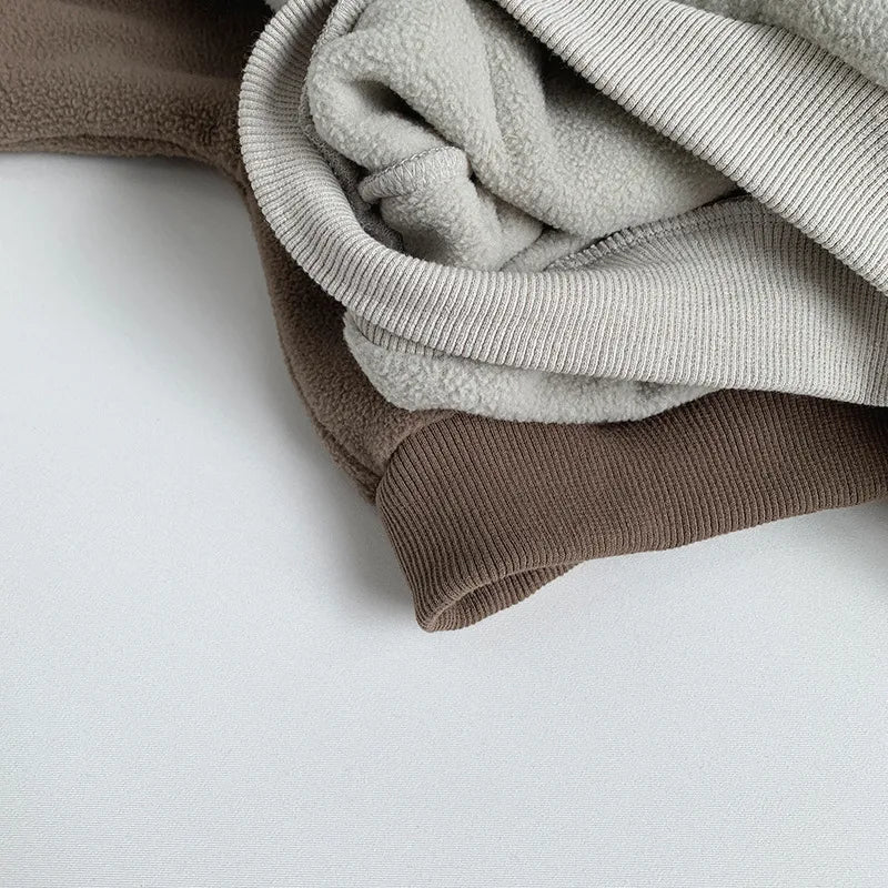 Stack of folded sweaters in brown and gray on a white surface