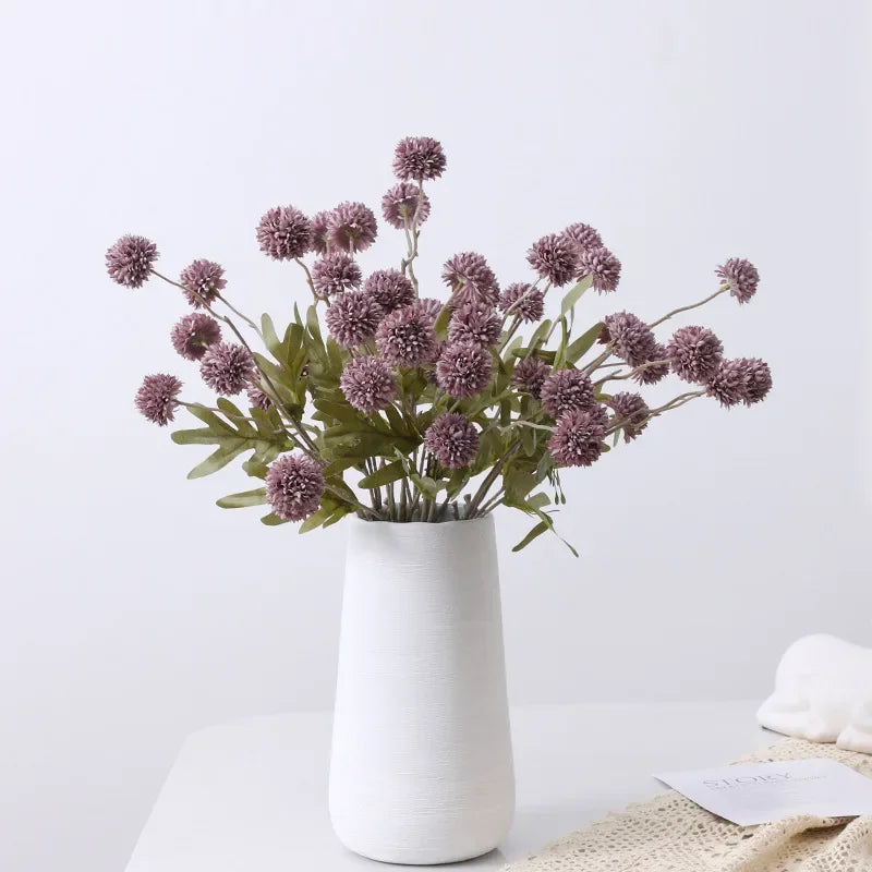 White vase with purple flowers on a light gray background
