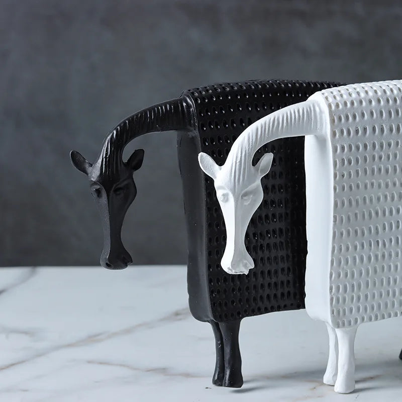 Two decorative animal-shaped objects, one black and one white, on a marble surface with a dark background.