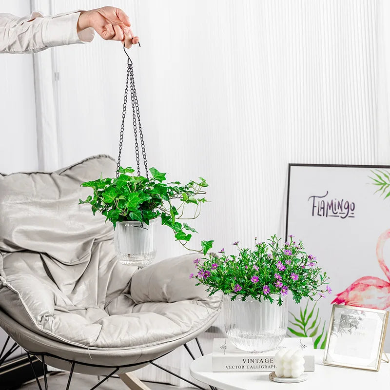 Hanging plant in a Transparent hanging plant pot with metal chain and ribbed design for indoor plant displayed in a modern living room with decor elements.