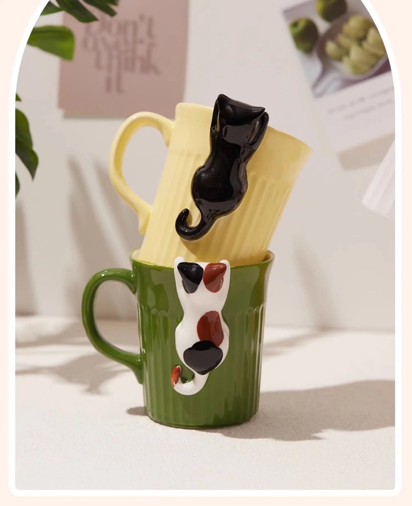 Green and yellow ceramic cat mugs with a 3D cat climbing over the rim.