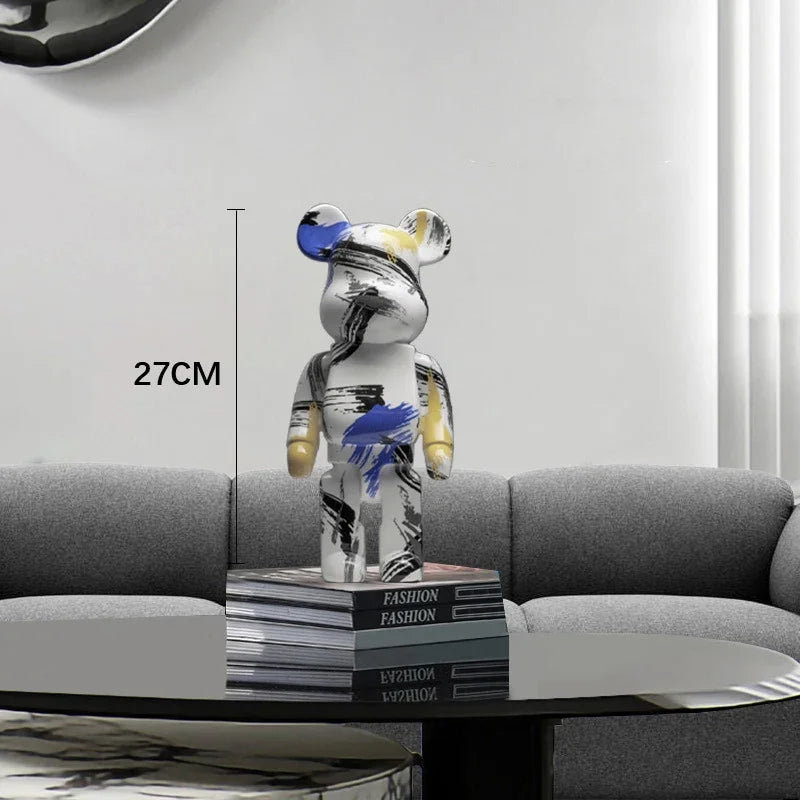 Stylized bear figure on fashion magazines with a 27CM label, placed on a table.