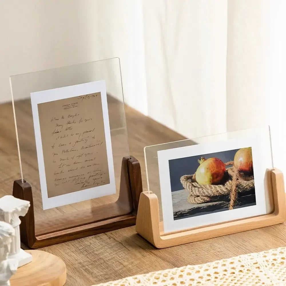 Two photo stands on a wooden surface with one holding a letter and the other a photograph.