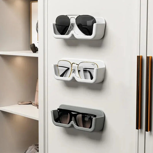 Three pairs of sunglasses displayed on a white wall-mounted shelf.