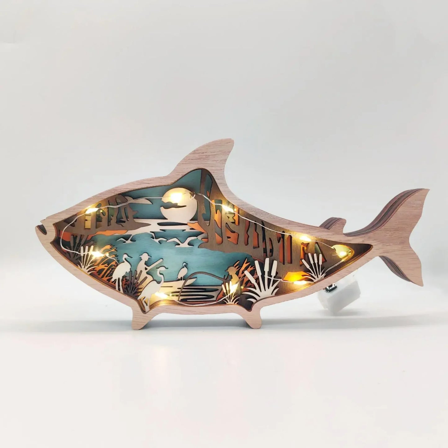 Lit up Wooden fish-shaped cutout with laser-cut scenes on a white 