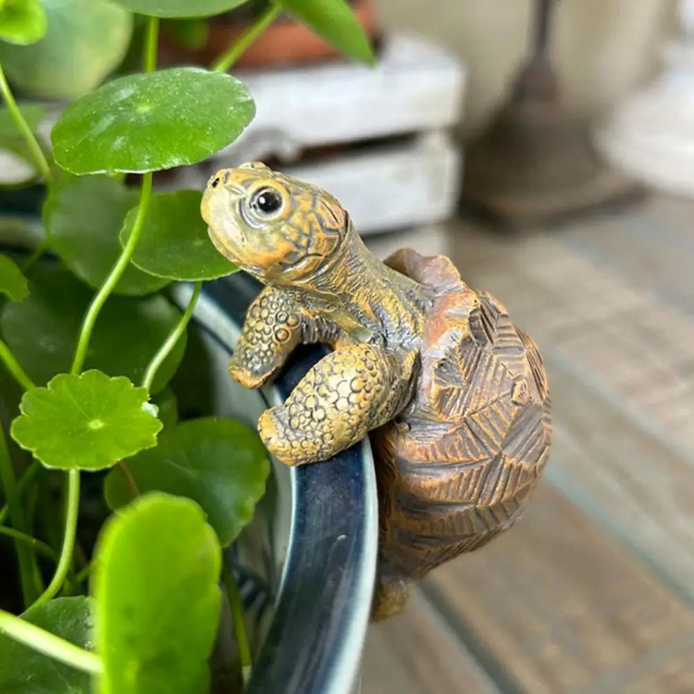 Decorative turtle figure on a plant pot with green leaves in the background