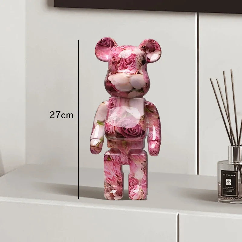 Pink floral-patterned bear figure on a white surface with a diffuser in the background