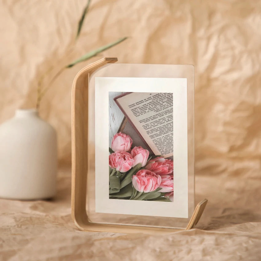 Framed picture of pink flowers and text on a wooden surface with a blurred background