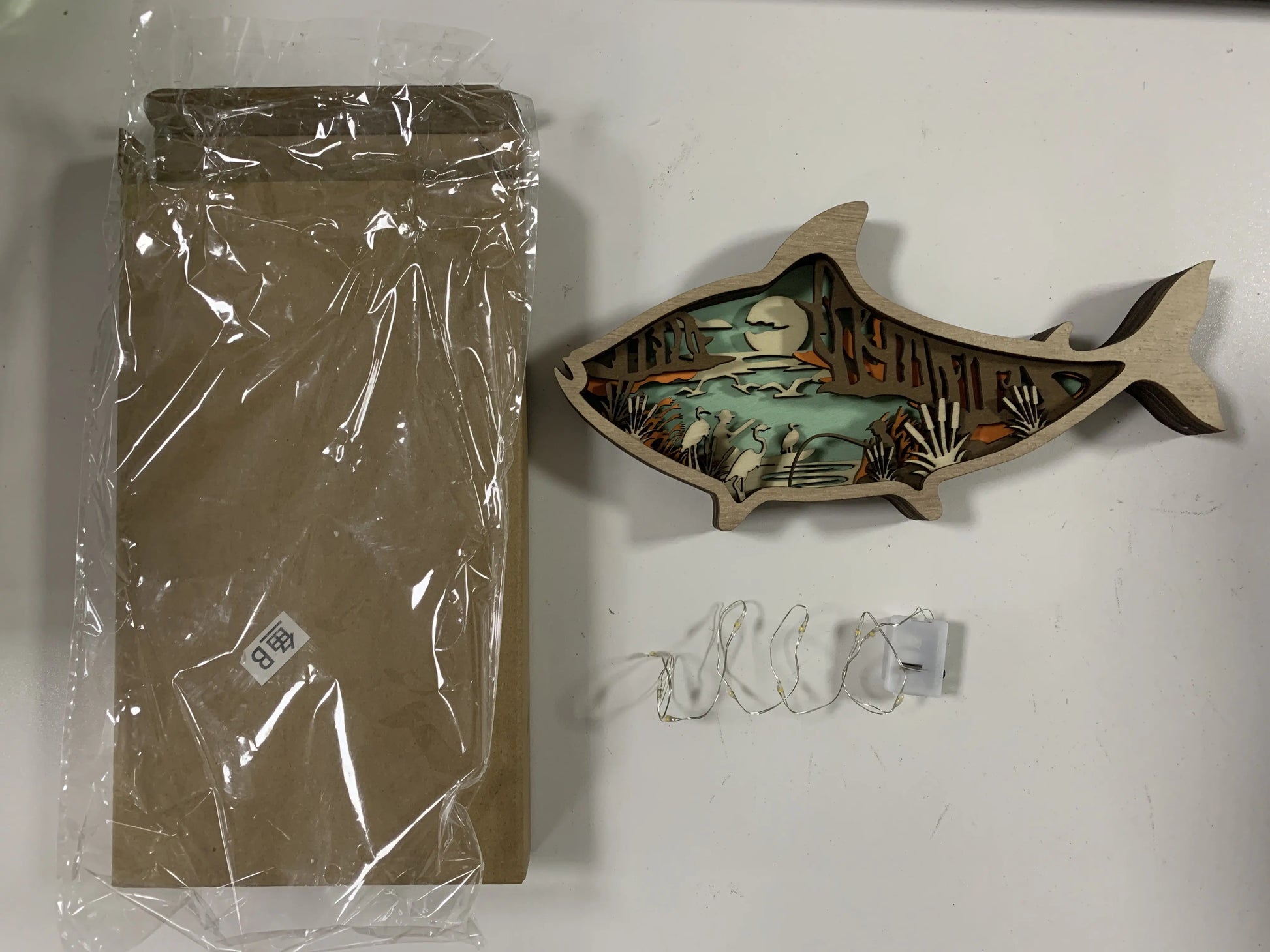 Decorative wall art fish with packaging on a white surface