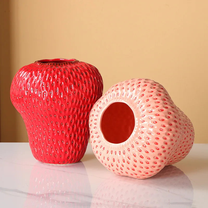 Two textured ceramic vases, one red and one pink, on a reflective surface with a beige background.