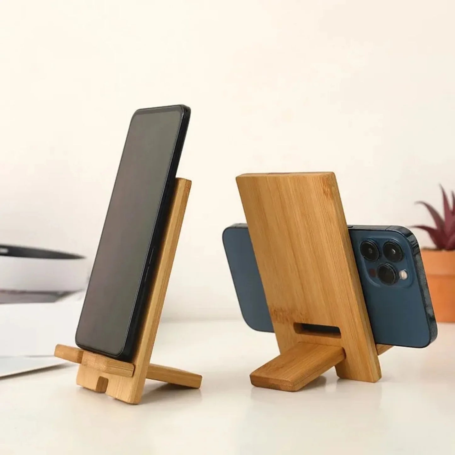 Bamboo desktop phone holder with angled stand and charging slot for smartphones.