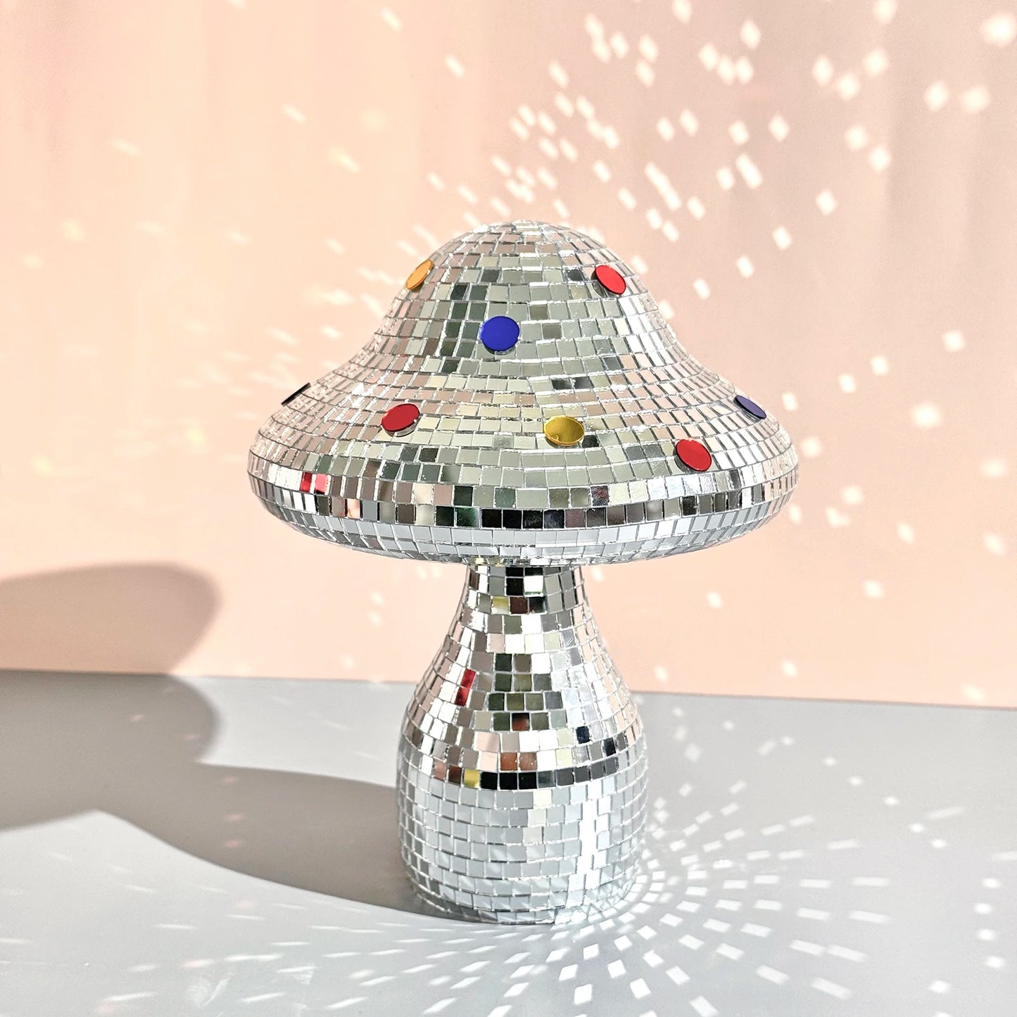 Silver disco mushroom ornament with colorful buttons on a light pink background