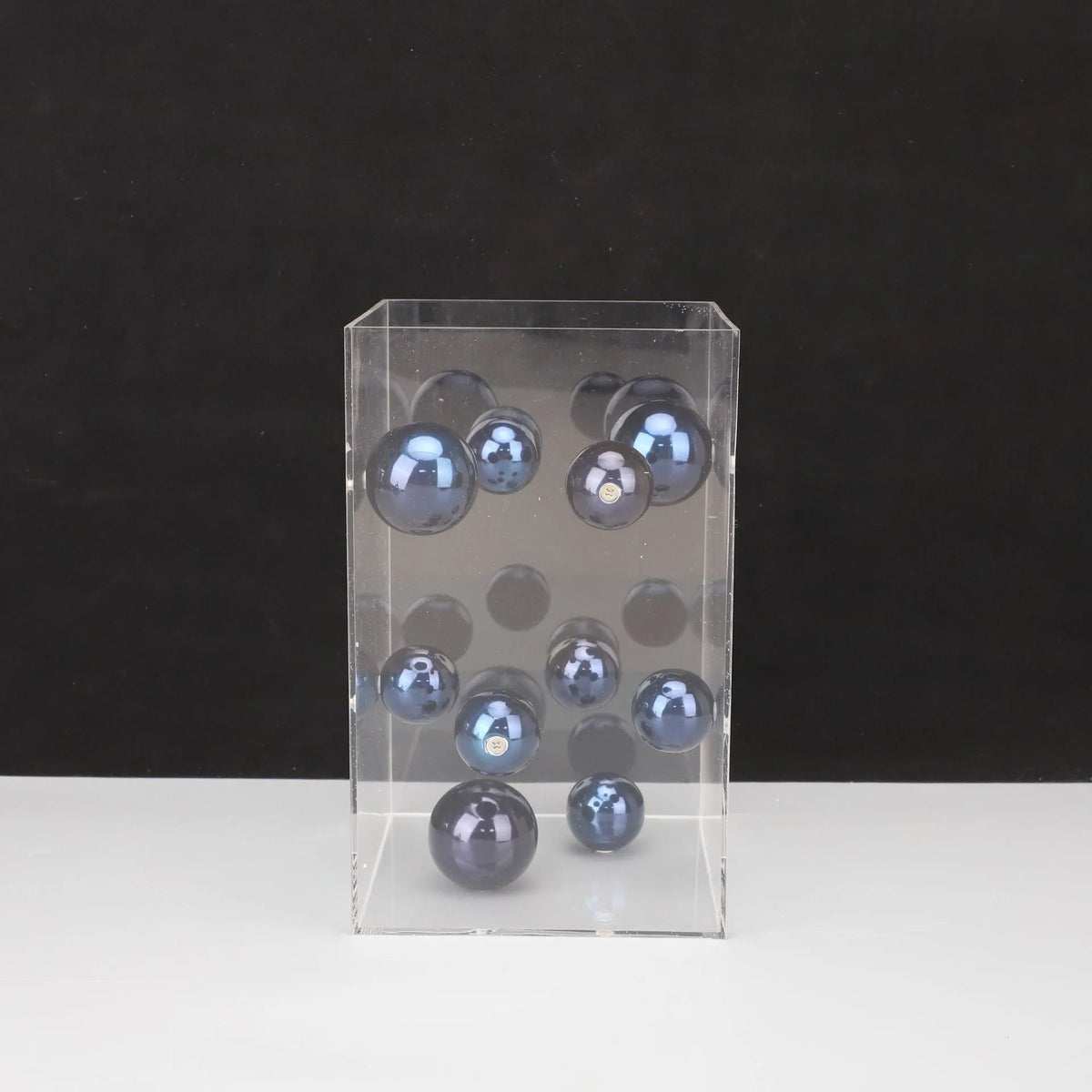 Clear acrylic display box with blue spherical objects on a black background