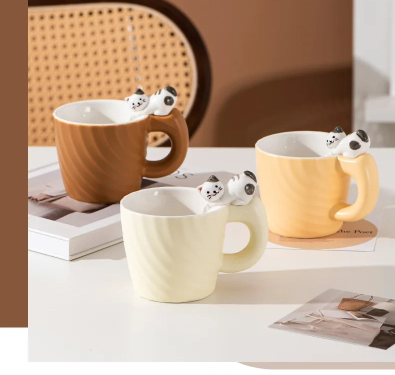 Three cute cat-themed mugs on a table with a blurred background