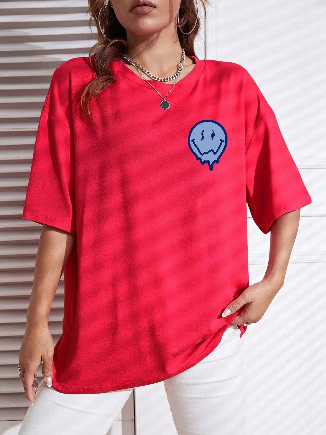 Person wearing a red t-shirt with a blue smiley face design against a white background