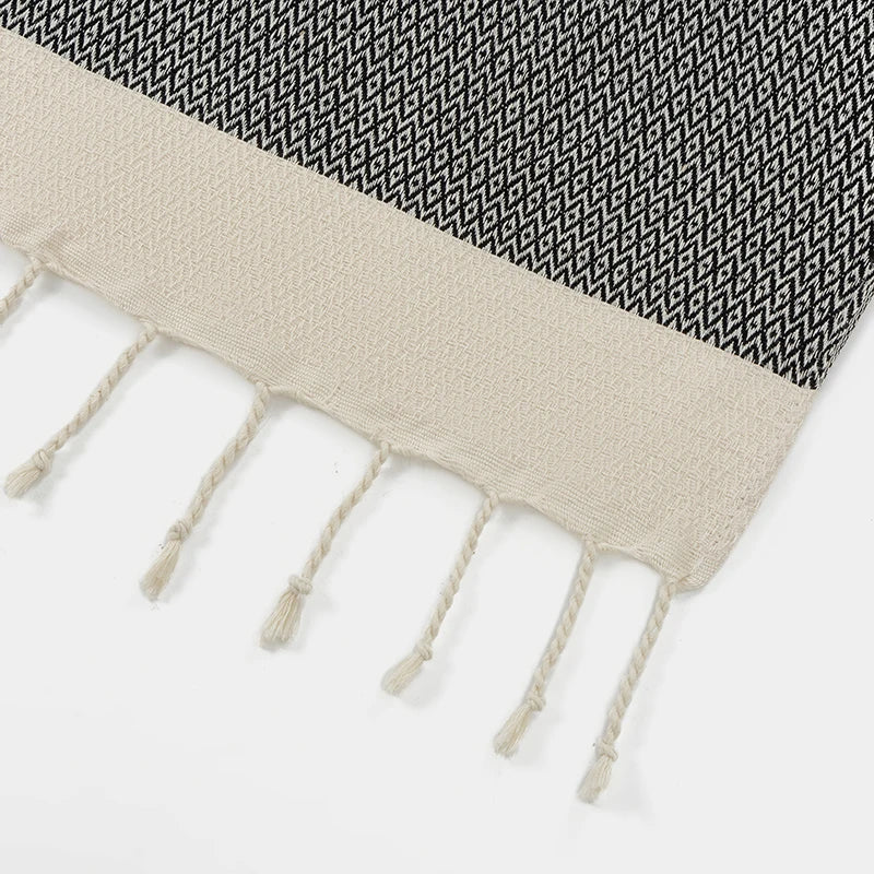 Textured fabric with black and white pattern and beige fringe on a white background