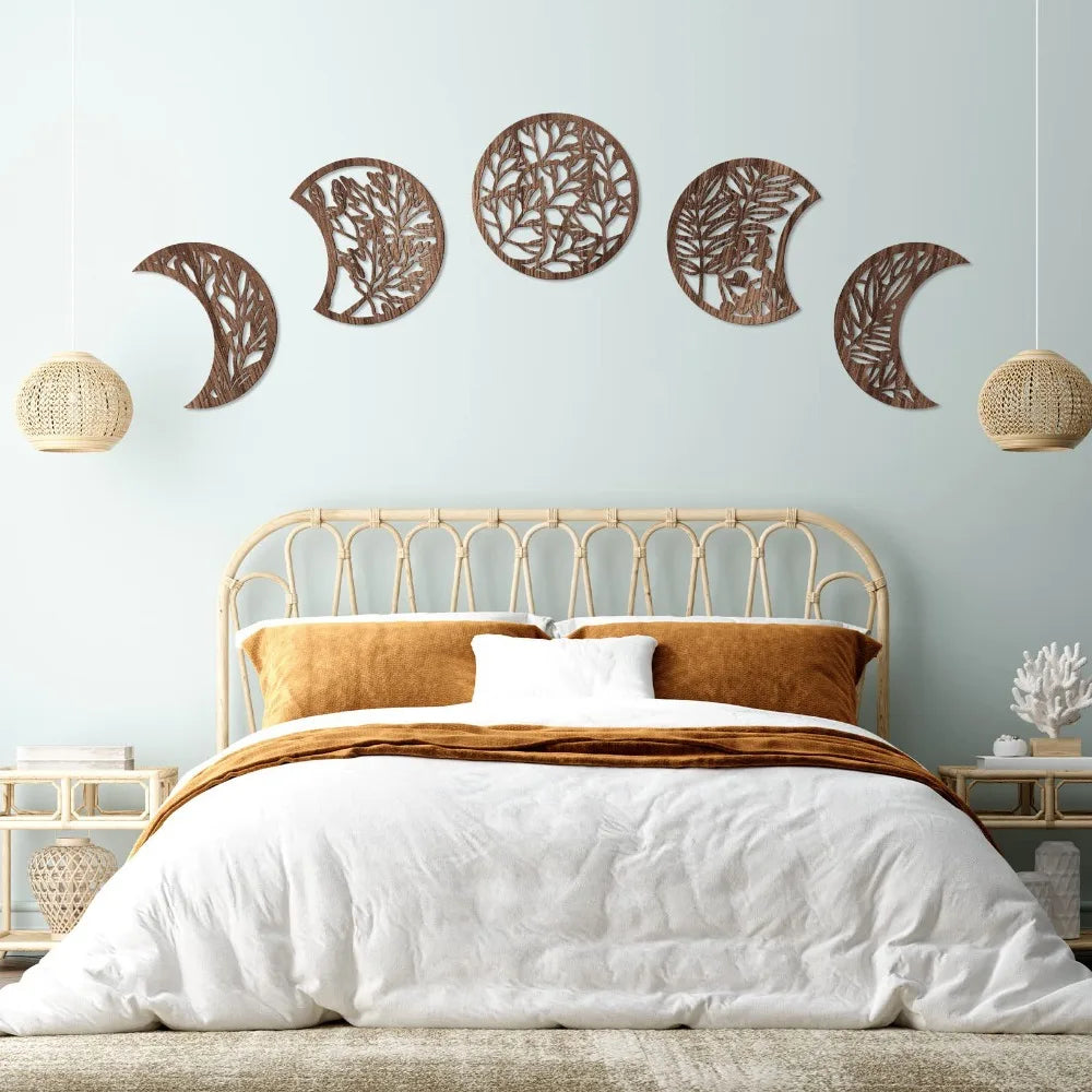 Wooden moon phase wall art set with botanical cut-out design hanging above bed in Nordic boho bedroom decor