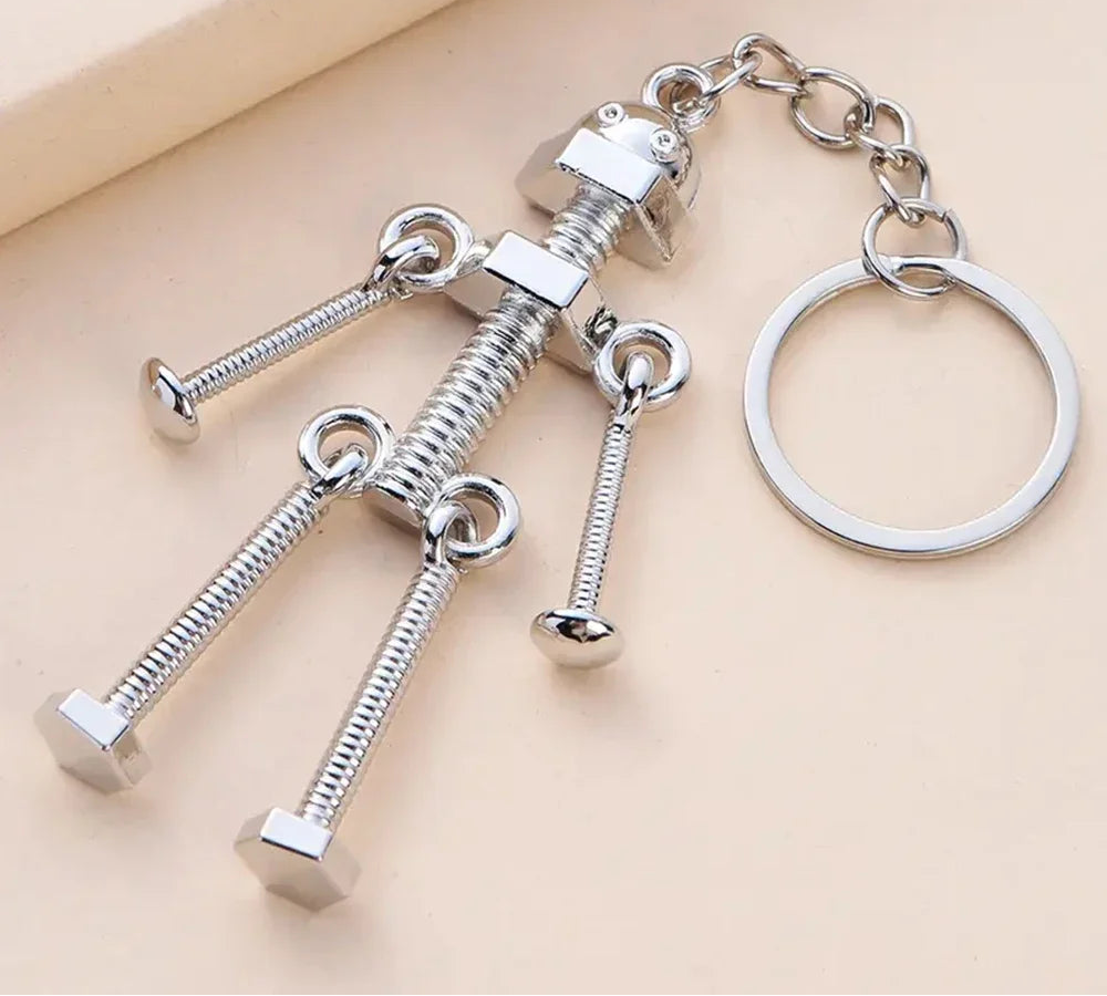 Silver keychain with mechanical design on a beige background