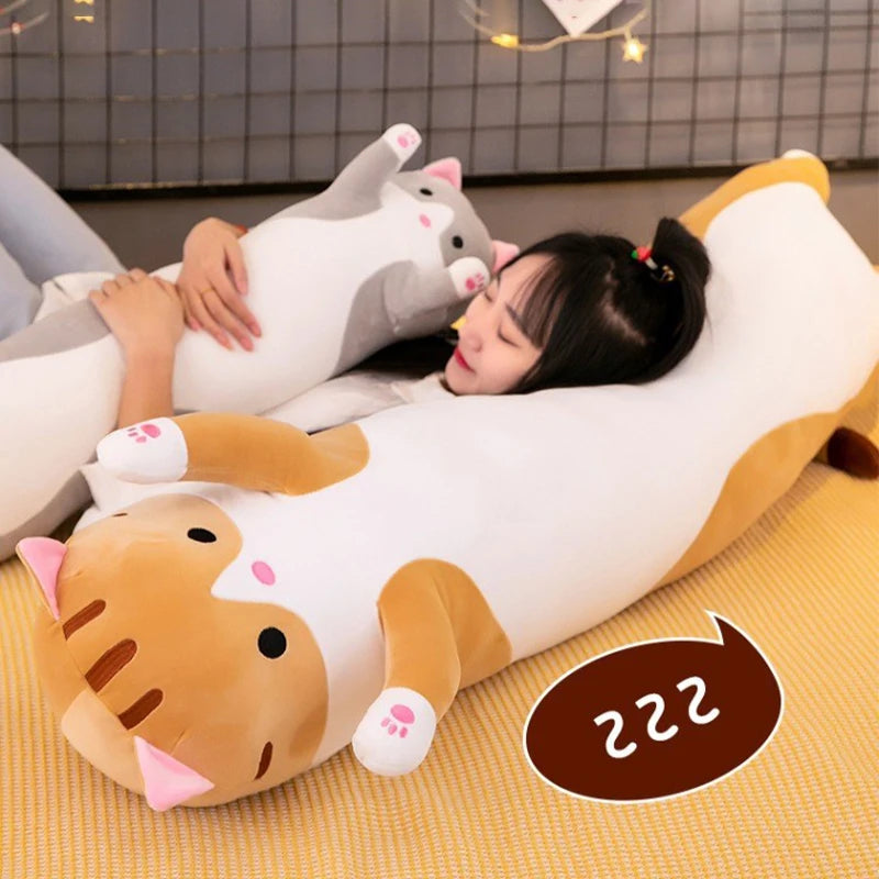 Person lying on a large cat-shaped plush pillow with a grid wall in the background