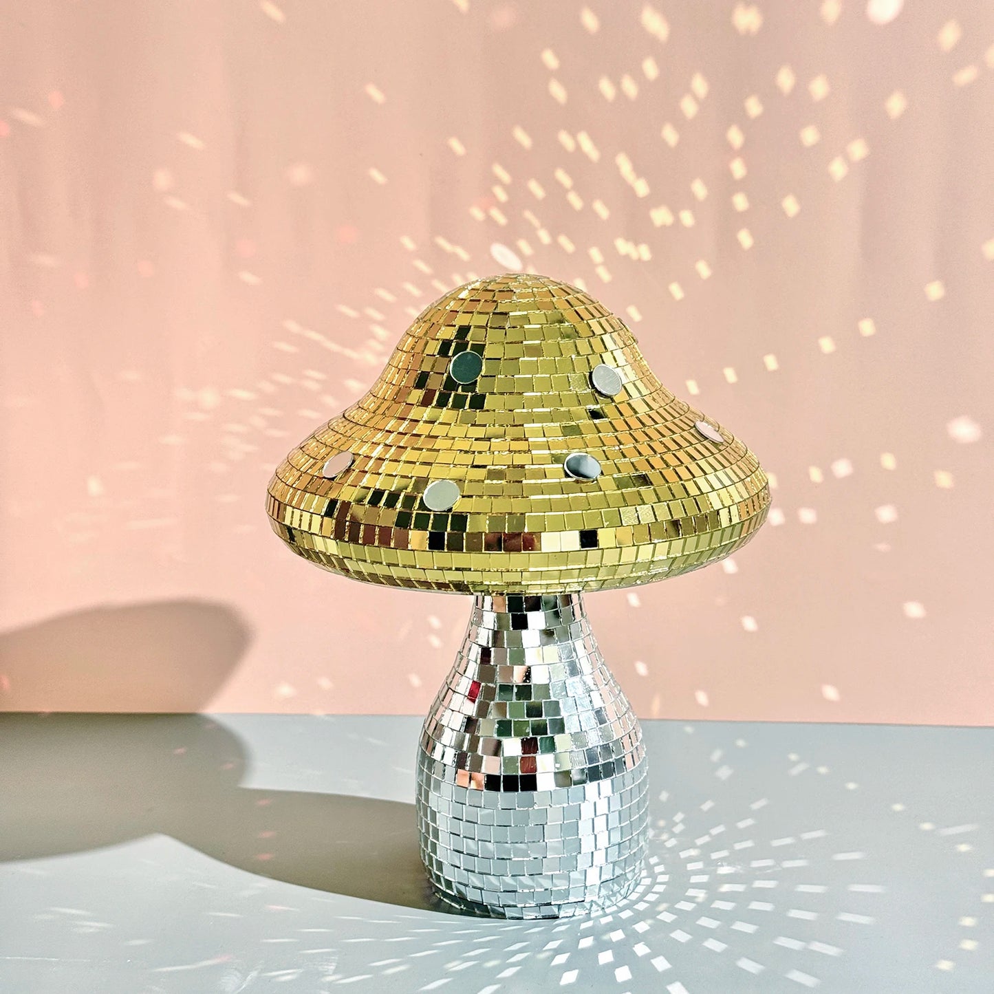 Gold and silver disco mushroom ornament on a pink background