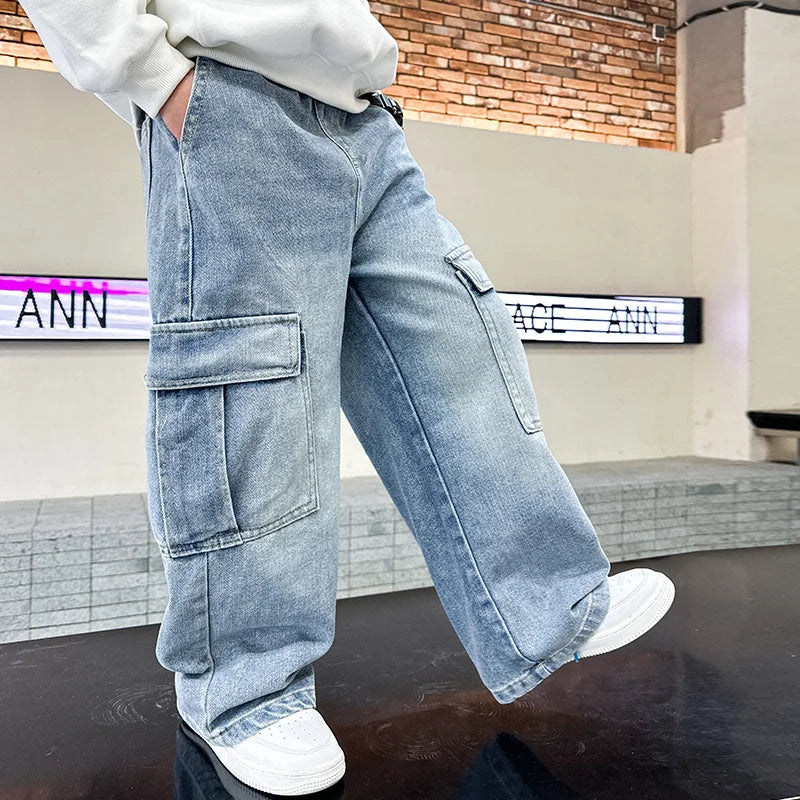 Person wearing light blue cargo pants in an indoor setting with a brick wall background.