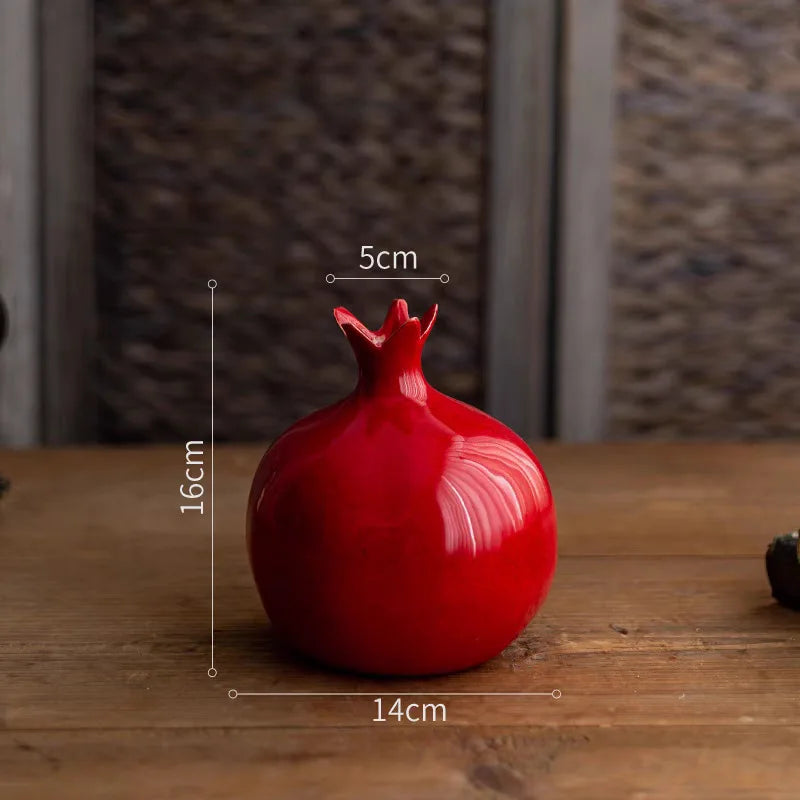 Red ceramic pomegranate-shaped object with measurements on a wooden surface