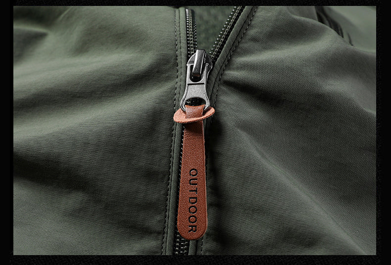 Close-up of a green jacket with a brown zipper pull and 'Outdoor' branding.